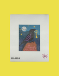A needlepoint canvas featuring a stitched design of a black bird with purple wing details perched on a brown rock, holding a gold key under a full moon and starry night sky. The canvas is displayed on a solid bright yellow background.